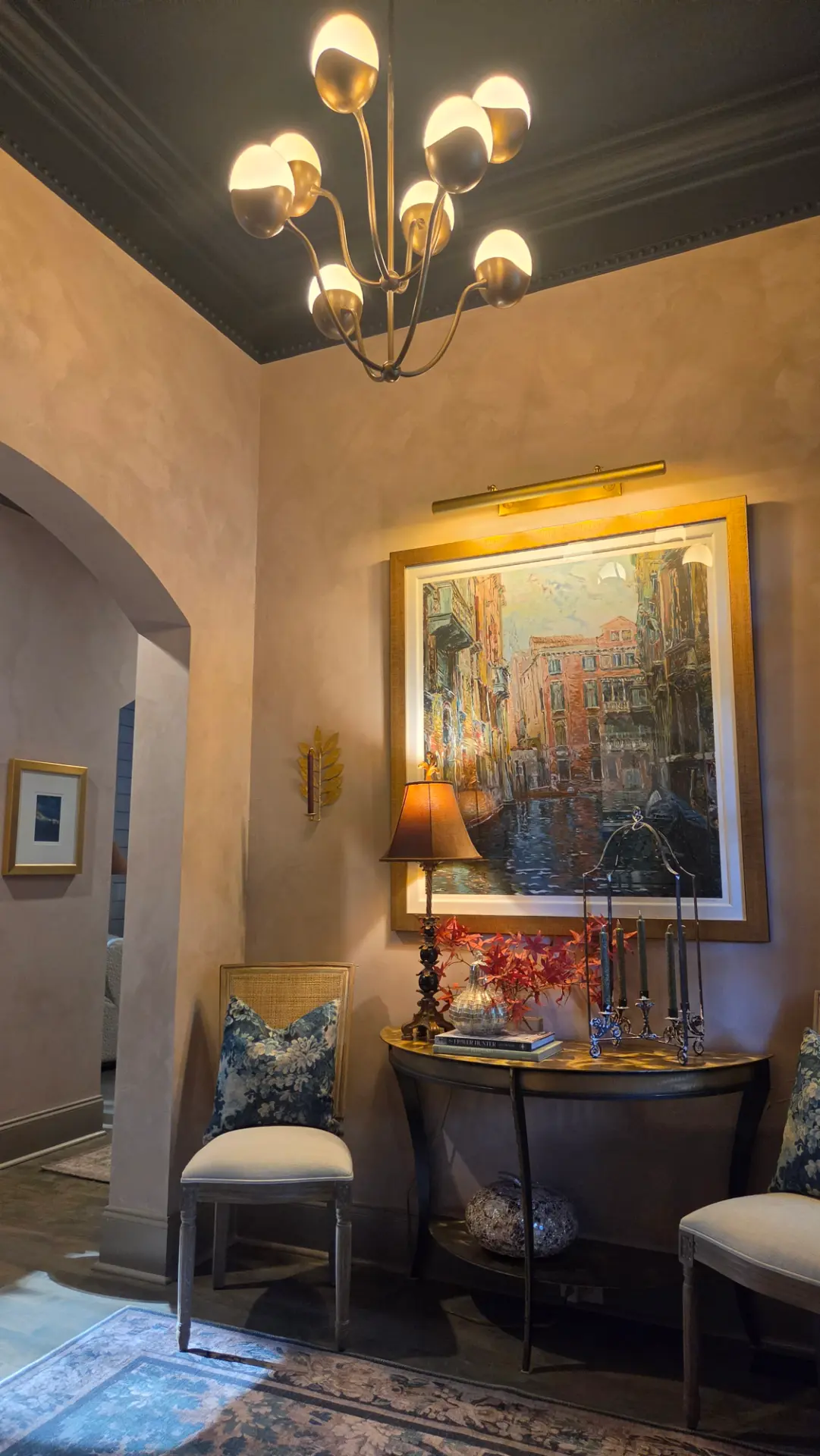 Arched doorway beside the framed Venice artwork, with warm trim, lime-painted walls and the sculptural chandelier overhead