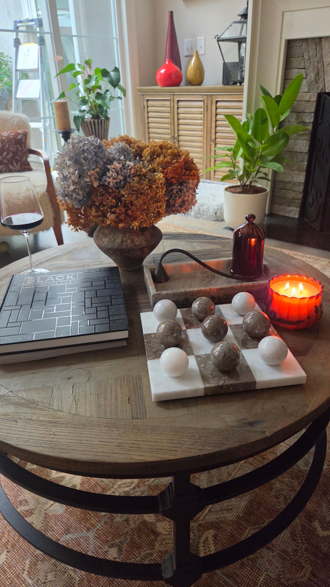 Coffee table layered with dried hydrangeas, candlelight, books and a marble tic-tac-toe set